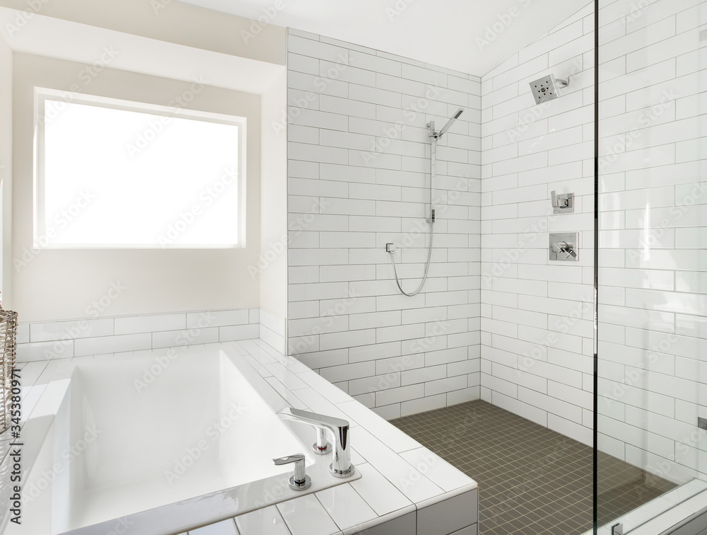 Bathtub and shower in new luxury home with white walls and white subway tile Bathtub and shower in new luxury home with white walls and white subway tile