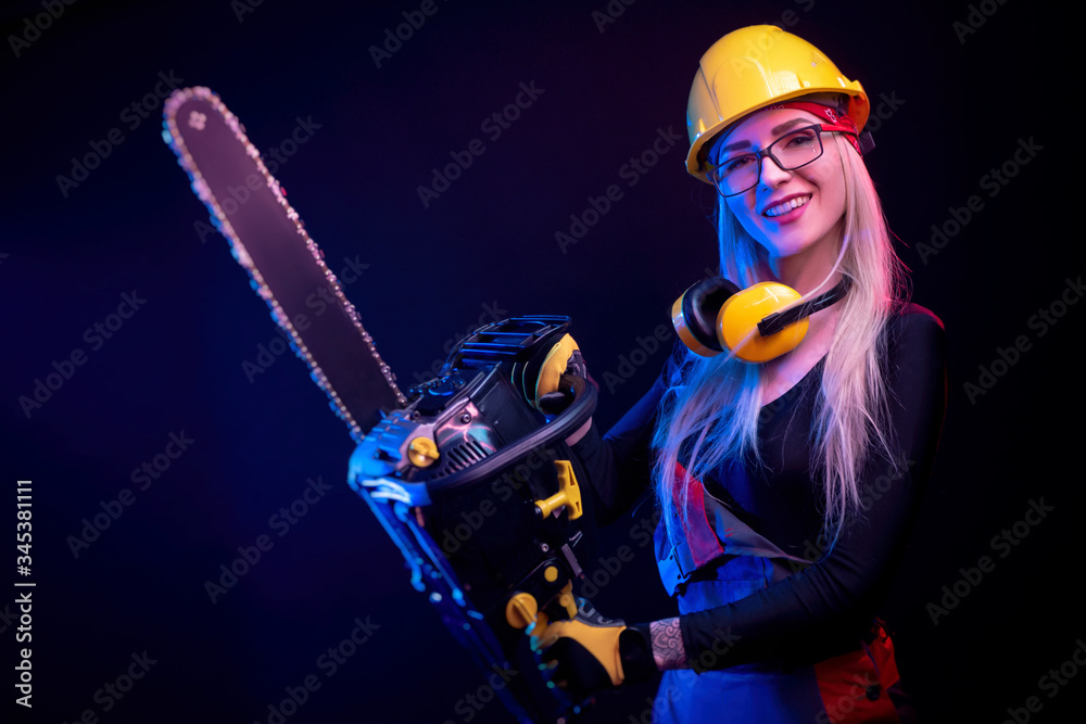 a girl with a chainsaw in overalls on a black background in a neon light