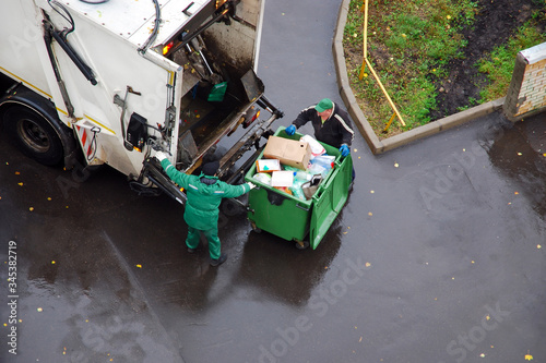 garbage removal in residential area, garbage men loading household rubbish in garbage truck