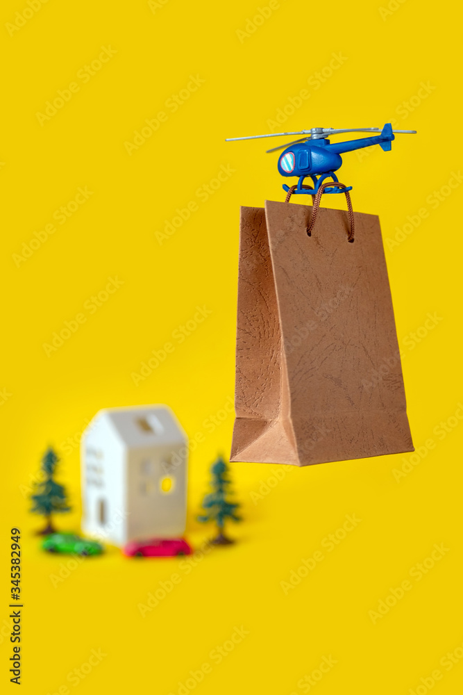 Yellow paper bag gift toy house tree delivery helicopter fly copy space background Yellow paper bag gift toy house tree delivery helicopter fly copy space background