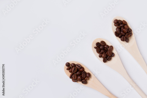 Wooden spoons with roasted coffee beans. Isolated on white background. Top view flat lay.