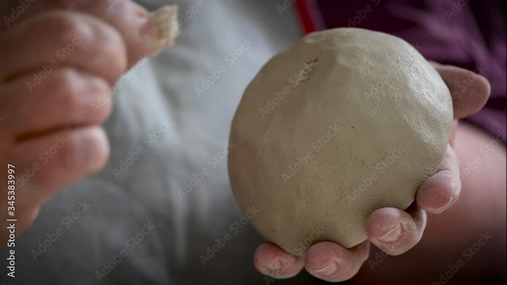 Hand drückt einen Stempel mit Initialen in den Boden einer Schale aus weichem Ton