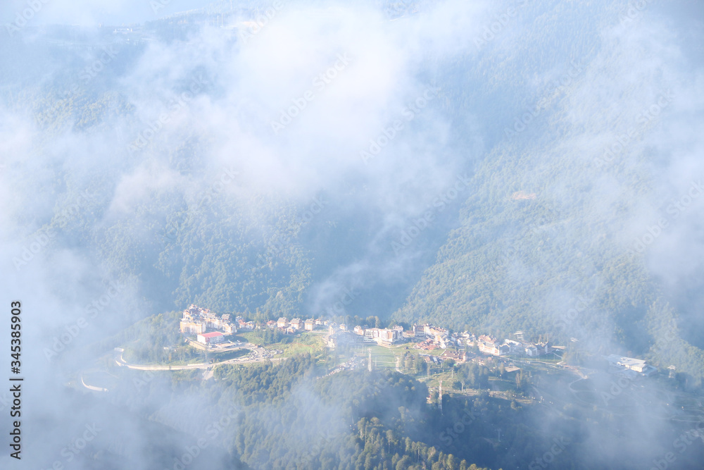view through cloud on village in mountain. Bird's eye view through clouds on mountainous city
