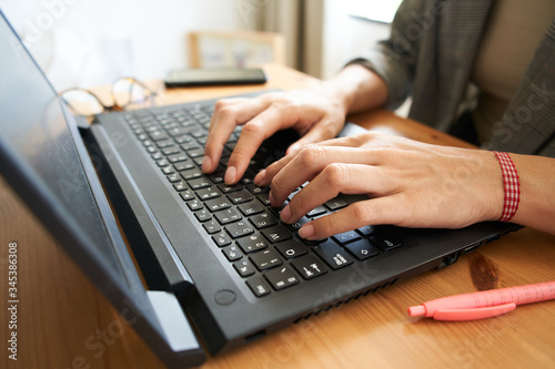 Hands of a business woman typing on her computer on a wooden table