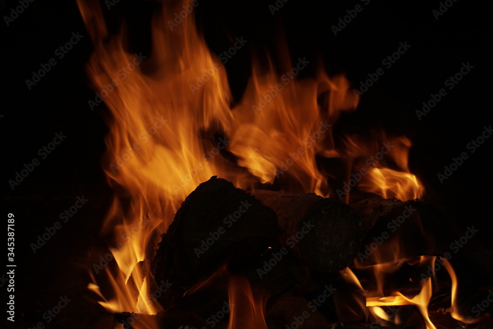 firewood burning in fireplace on dark background
