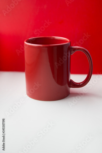 Red ceramic mug on a white and red background.