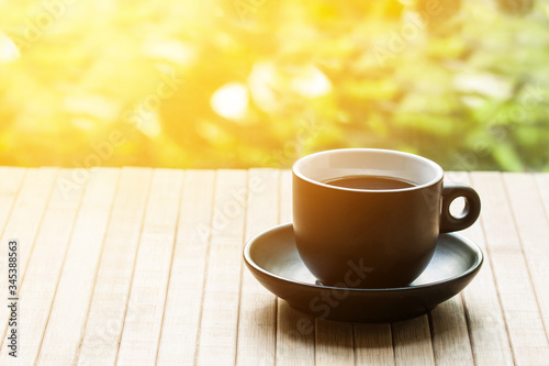 A cup of coffee on wooden table cloth in the open air with sunlight flash effect