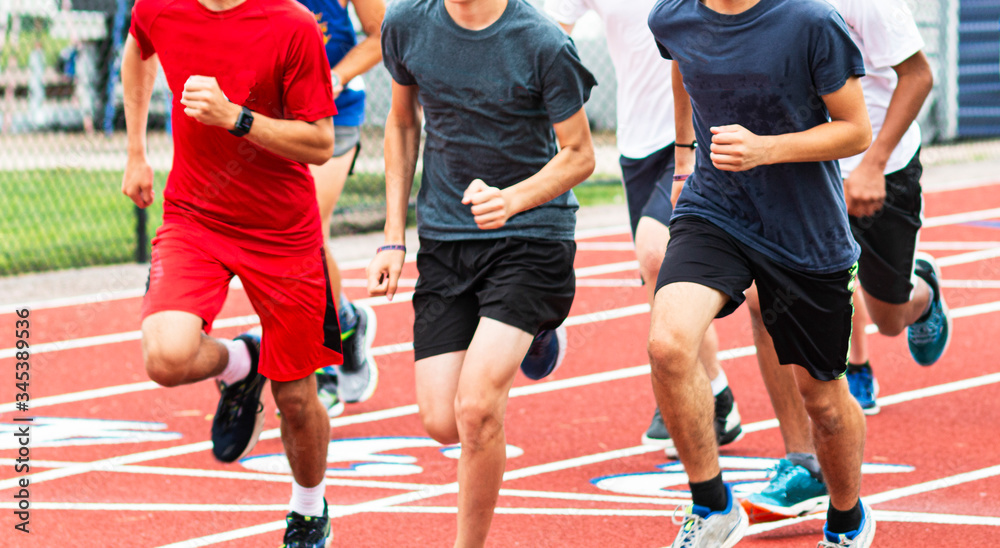 Boys run training together in a group on a red track Boys run training together in a group on a red track
