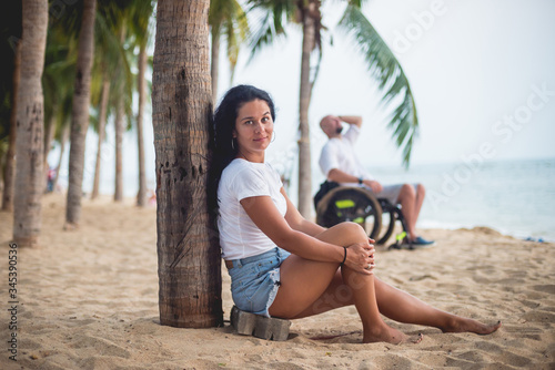 Disabled man in a wheelchair with his wife on the beach.