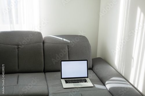 Open laptop on the couch. Modern comfortable workplace, distance work. Empty place for text, copy space.