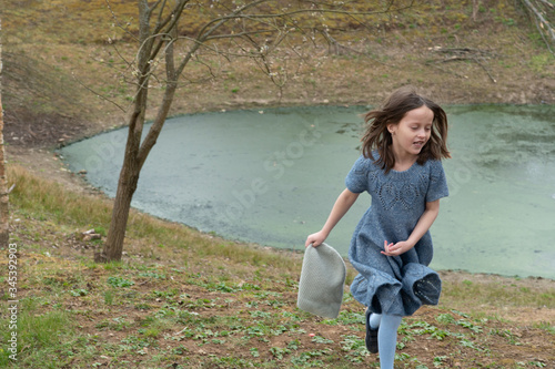 
Little girl in a woolen dress near a small lake in spring
