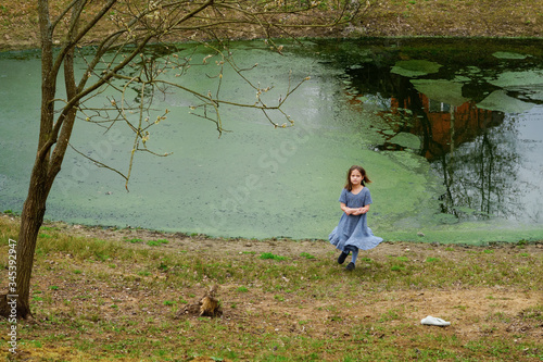 
Little girl in a woolen dress near a small lake in spring
