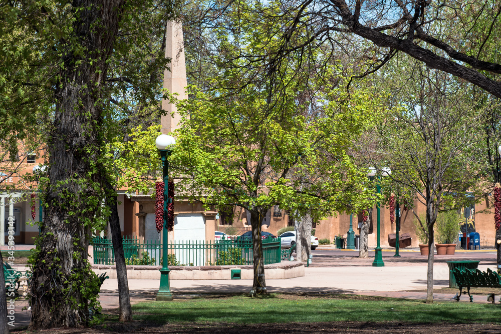 Fototapeta premium Historic obelisk, trees, and lampposts at Santa Fe Plaza in New Mexico