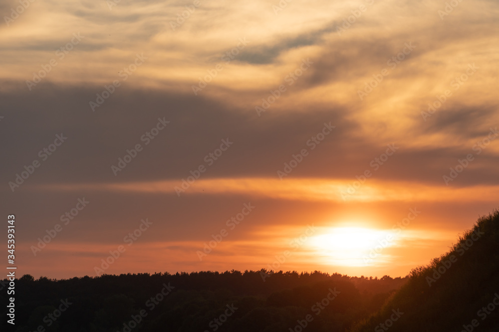 white and gray clouds are illuminated by the bright light of the setting sun. The sun is already on the horizon. Sunset or sunrise over the forest white and gray clouds are illuminated by the bright light of the setting sun. The sun is already on the horizon. Sunset or sunrise over the forest