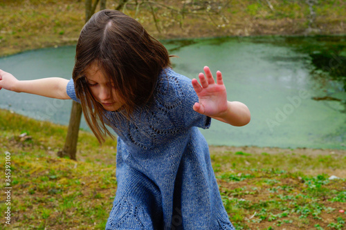
Little girl in a woolen dress near a small lake in spring