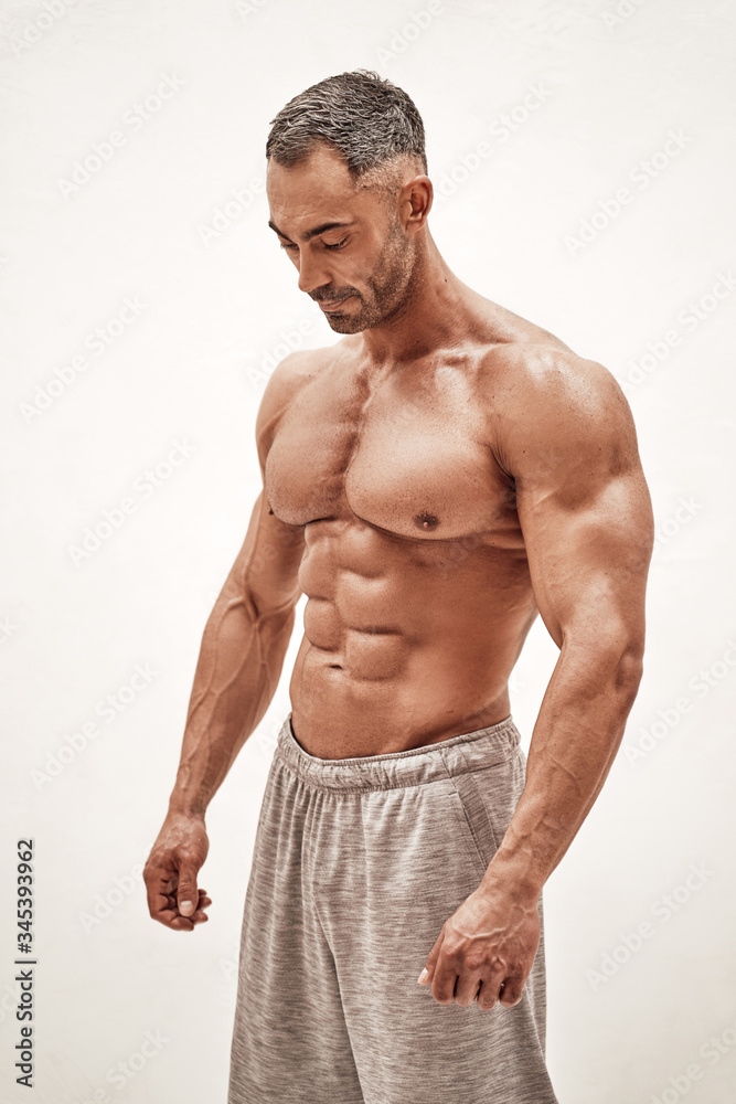 Fotografie Strong and powerful man bodybuilder looking down in a bright studio