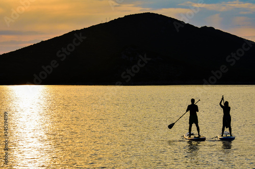 Sup boarding couple on sunset