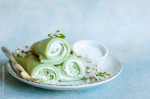 Delicious homemade green pancakes with blossoming cherry tree branches on sky blue background. photo