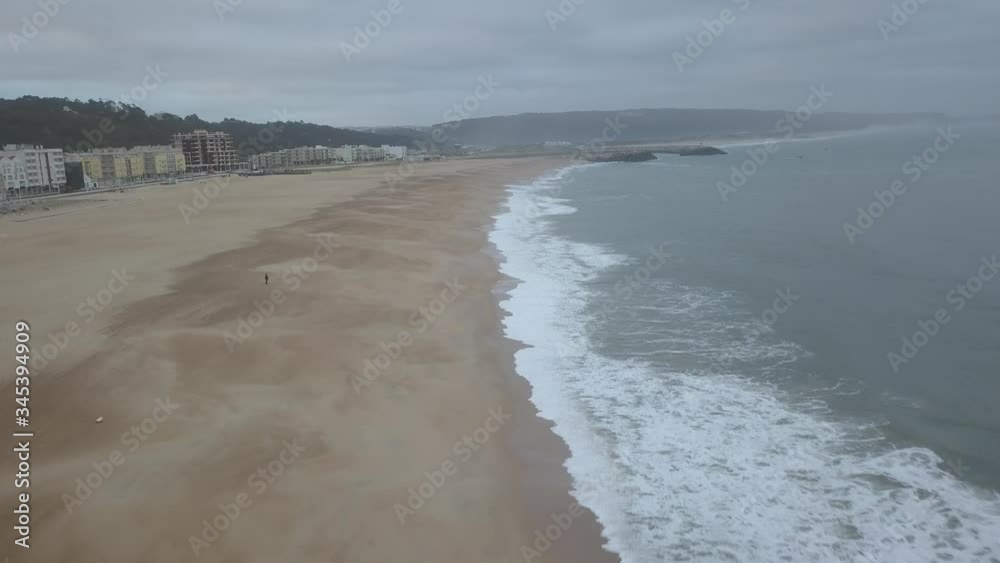 Flying over a sandy beach. Waves break on a sandy beach on the Atlantic coast, aerial View. Nazare, Portugal. (raw video). Flying over a sandy beach. Waves break on a sandy beach on the Atlantic coast, aerial View. Nazare, Portugal. (raw video).