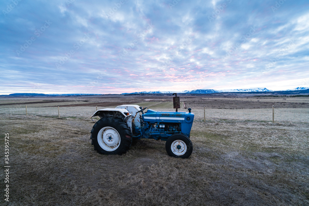 Agriculture stock picture. A small tractor on a field during the sunset time. Agriculture in Iceland, Scandinavia. Background photograph of a tractor Agriculture stock picture. A small tractor on a field during the sunset time. Agriculture in Iceland, Scandinavia. Background photograph of a tractor