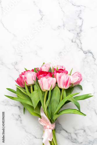 Bouquet of pink tulips on marble background with copy space for text or design