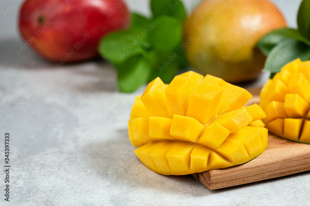 Mango halved on wooden cutting board with copy space for text. Fresh ripe tropical fruit mango