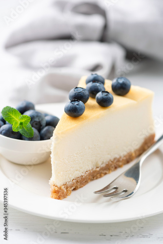 Obraz na plátně Slice of cheesecake topped with blueberries on a white plate