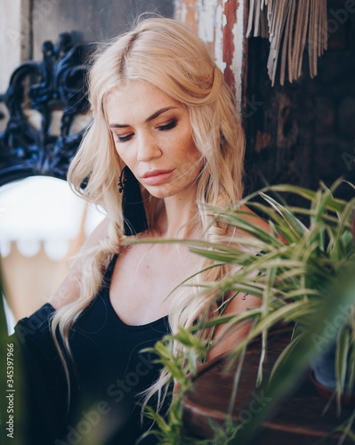 Fototapeta Naklejka Na Ścianę i Meble -  Portrait of beautiful young blonde in the black clothing of style of бохо in a summer arbour