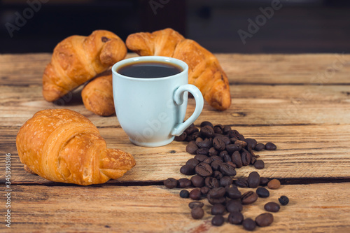 cup of coffee croissants and wall of wood