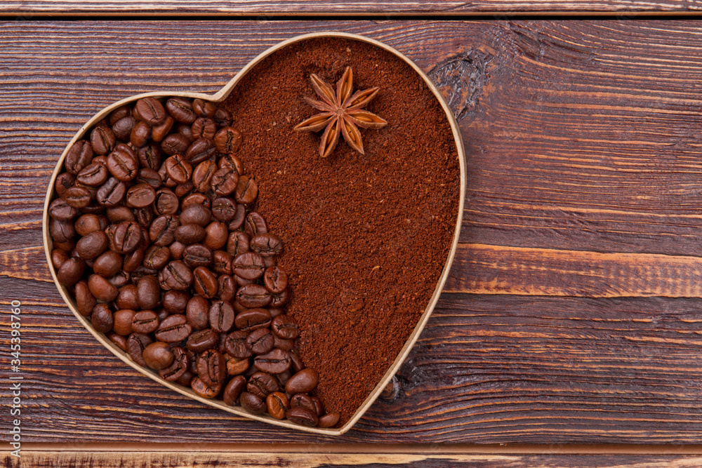 Heart made of coffee beans and instant coffee. Anise on the brown instant coffee. Brown wooden background. Heart made of coffee beans and instant coffee. Anise on the brown instant coffee. Brown wooden background.