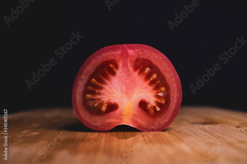 half a tomato lies on a cutting Board on a dark background. Ripe vegetables. Tomato set. Dark background. Healthy diet. Vegetarian food. Healthy diet. The design concept of the product.
