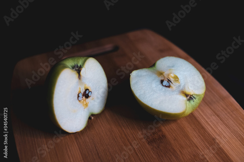 sliced green apple is lying on a wooden Board. Organic fruit. Healthy lifestyle. Sweet fruit. Vegetarian healthy food. Natural background. Dark background.