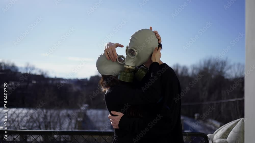 lovers in gas masks kiss and hug on the balcony during the coronavirus epidemic