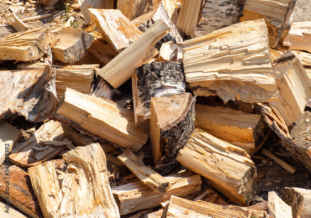 Pile of chopped birch wood is lying on ground. Natural background. Pile of split birch firewood