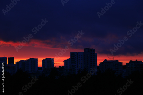 Beautiful sunset in the city. Silhouette of houses and construction cranes. Selective focus.