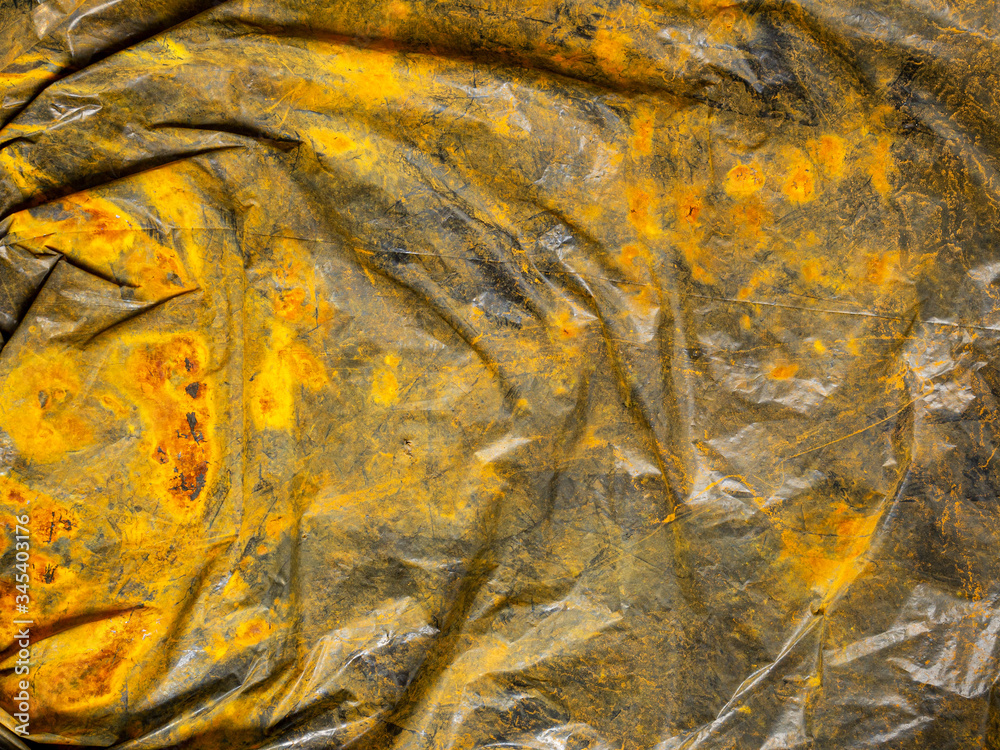 Background looks like a surface a black plastic bag stained with rust. The concept of cleaning nature from industrial and household waste. Background looks like a surface a black plastic bag stained with rust. The concept of cleaning nature from industrial and household waste.