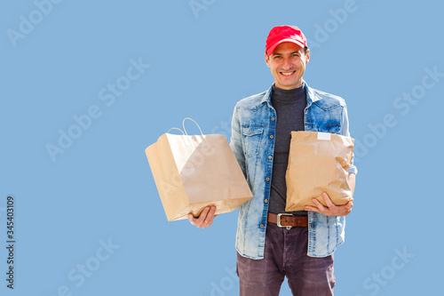 Delivery man in mask and gloves bring fresh food to customer's home. Stay home. Online shopping concept. blue background