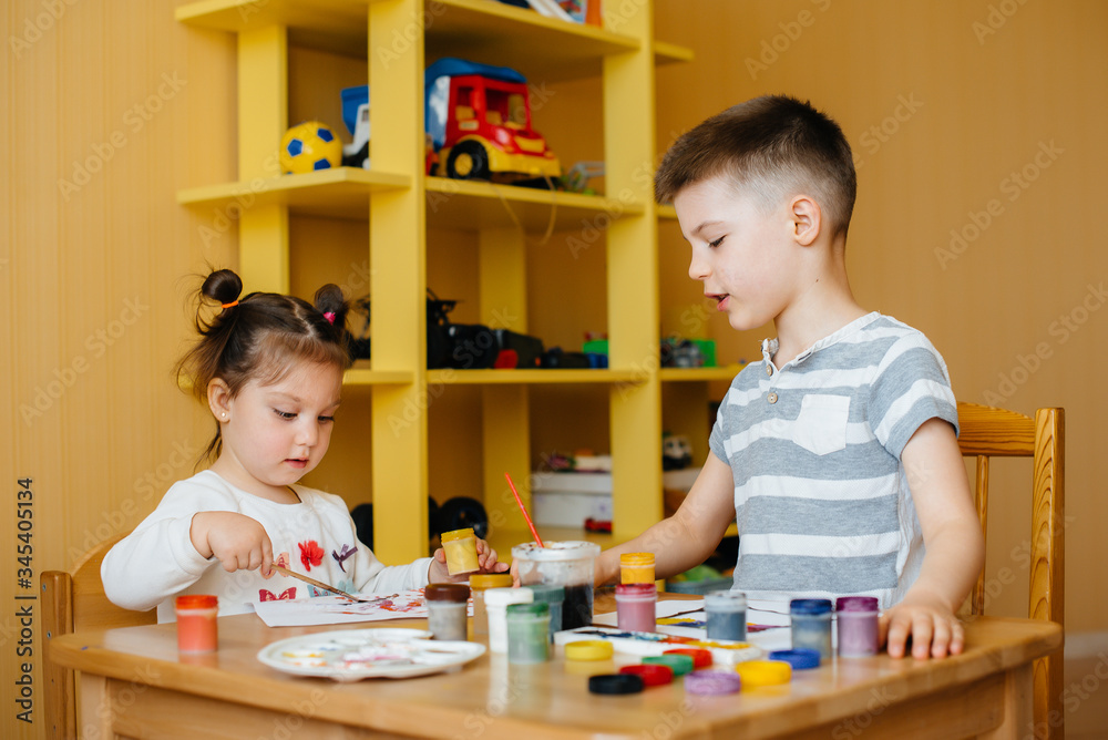 Fototapeta premium A boy and a girl play together and paint. Recreation and entertainment. Stay at home