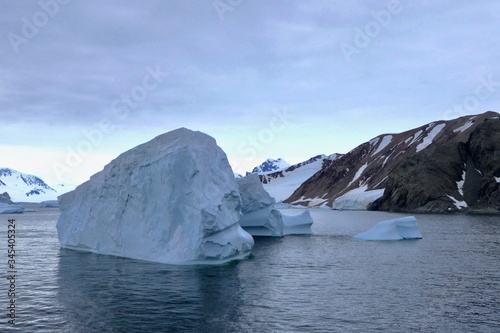 Iceberg in antarctic ocean with mountain, stormy sky, Antarctica