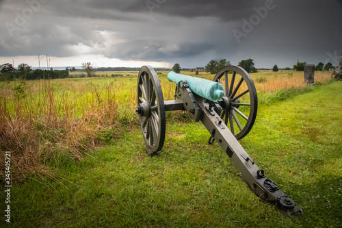 A civil war cannon points across the battlefield at Cemetery Ridge as storm clouds gather