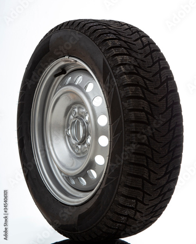 Car wheel and winter studded tire on white