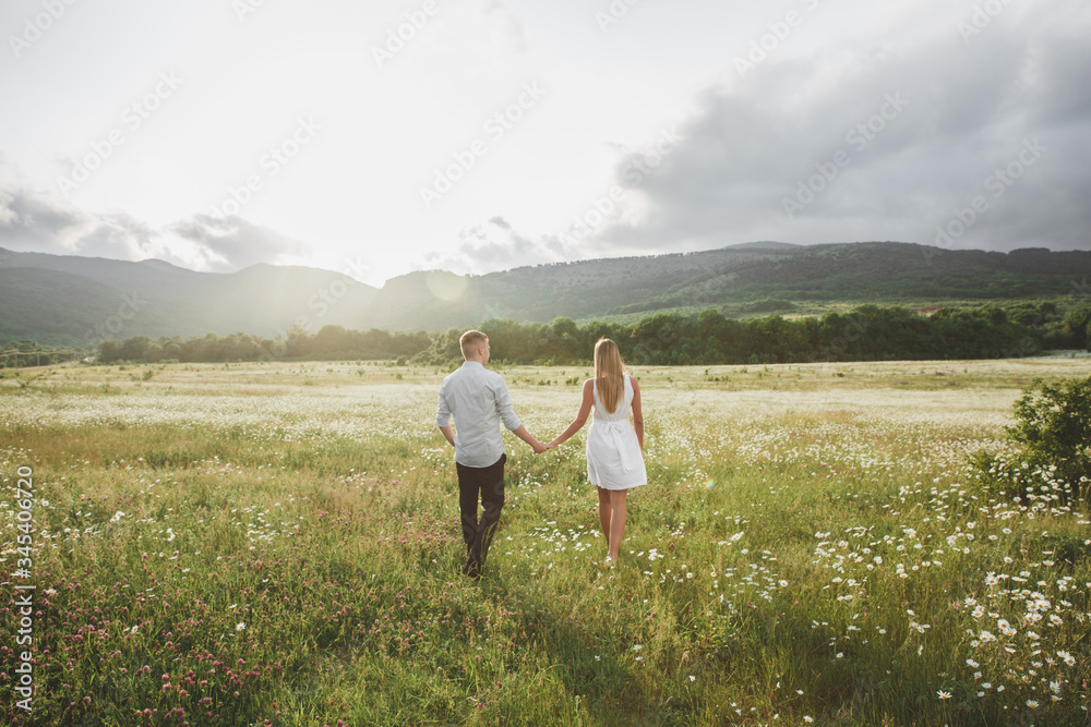 lovers in a chamomile field against the background of mountains