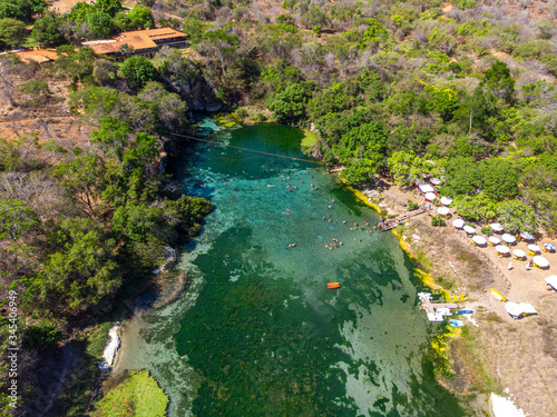 Aerial of Tourists swimming and enjoying the summer on beautiful and crystalline green water at River Pratinha, Iraquara, Chapada Diamantina, Bahia, Brazil. Drone slowly moving down. photo