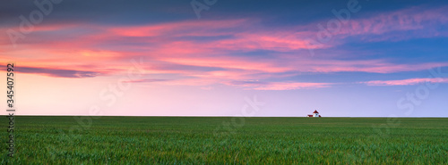 Canvas Print panorama of farm landscape with little house on horizon and sunset sky with pink