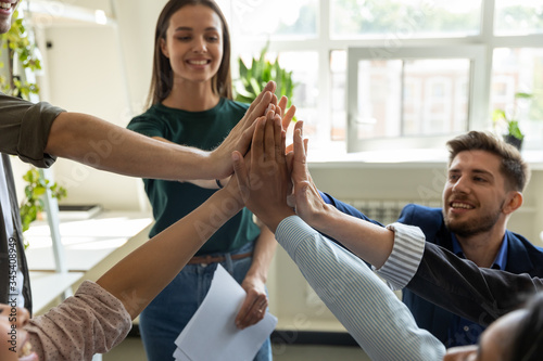 Cuadro en lienzo Diverse workers with happy female leader, coach giving high five at company meeting, woman teacher with students celebrating achievement, corporate success of teamwork, team building activity
