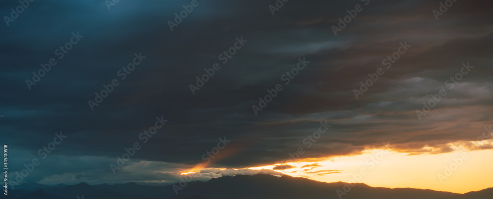 Storm at sunset with mountains in the background and rays of light breaking through the clouds