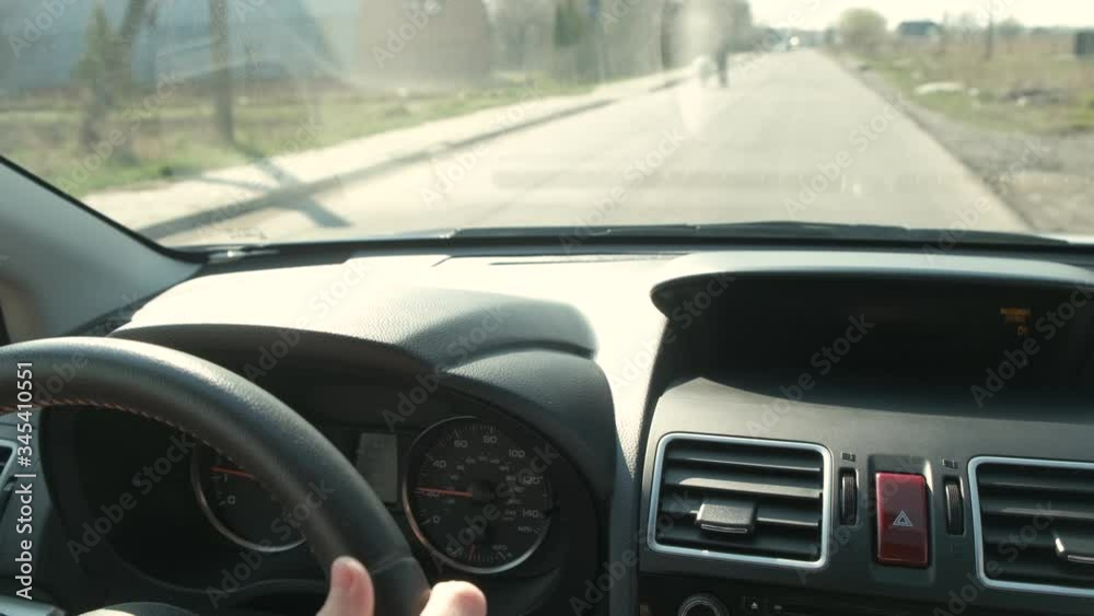 Close up view of woman hands holding steering wheel driving a car on city street on sunny day. Close up view of woman hands holding steering wheel driving a car on city street on sunny day.
