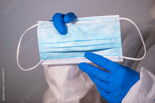 COVID-19. Facial masks on the pile. Epidemic background. Close-up. A medical worker in a protective anti-plague suit holds a maditsin mask with rubber disposable gloves photo