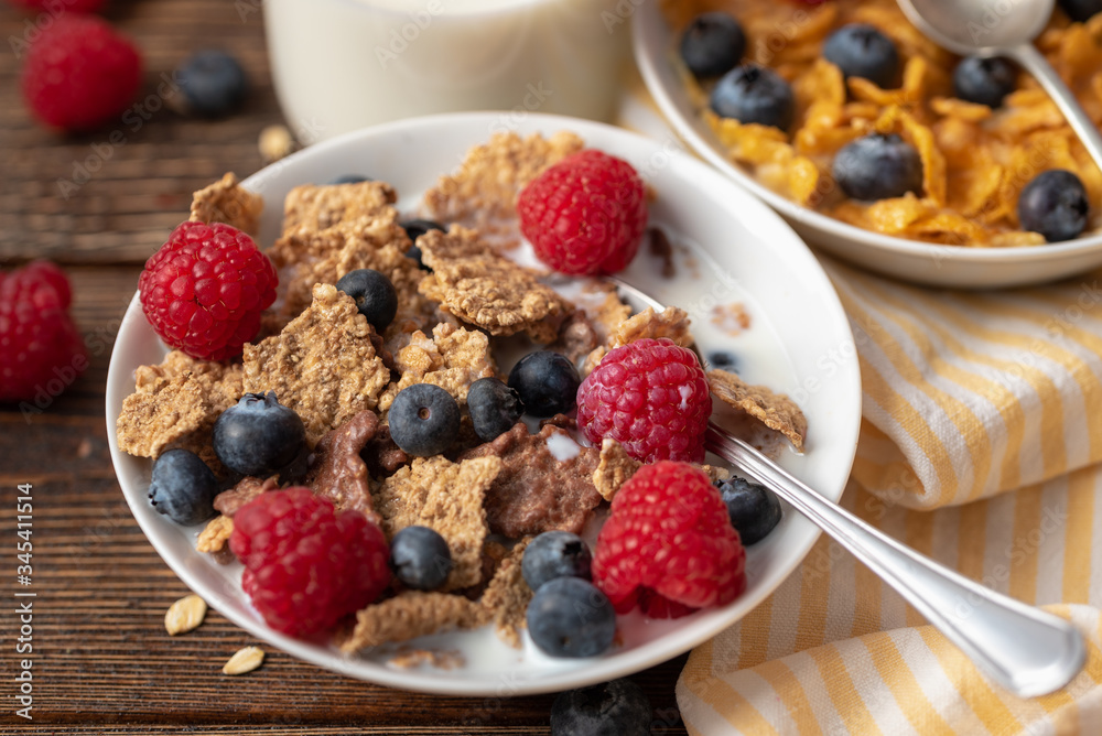 Cornflakes with blueberries and raspberries in white bowl on dark wooden desk. Cornflakes with blueberries and raspberries in white bowl on dark wooden desk.