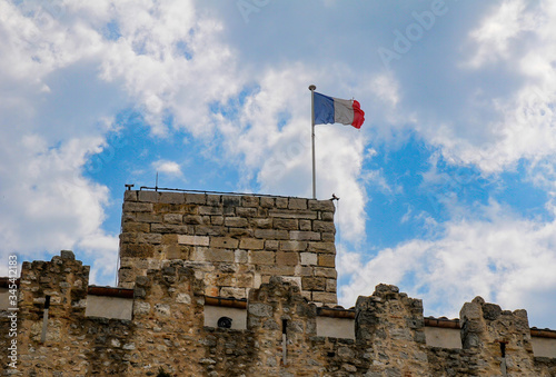 French national flag waving over Grimaldi castle in Antibes, French Riviera, France